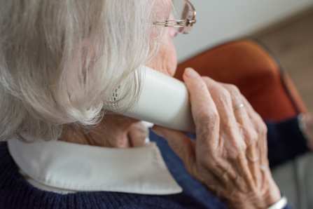 Eine alte Dame mit einem Telefonhörer am Ohr